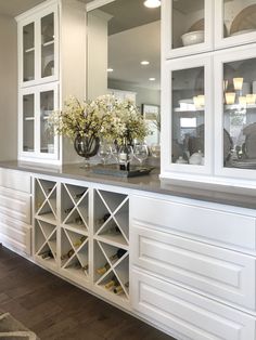 a white cabinet with wine glasses and flowers in it