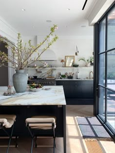 a kitchen with black cabinets and marble counter tops, along with an island in the middle