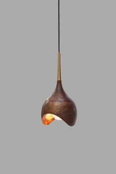 a wooden light hanging from a ceiling fixture with a black cord and an orange light bulb