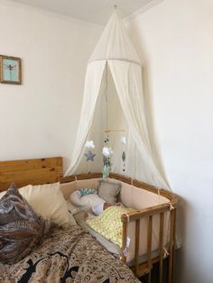 a baby crib in the corner of a room with a canopy hanging over it