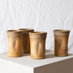 three brown cups sitting on top of a white table