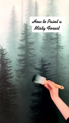 a person holding a paintbrush in front of a painting with trees on it and the words how to paint a misty forest