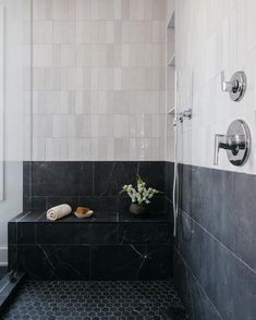 a black and white tiled bathroom with two vases on the shelf next to the shower