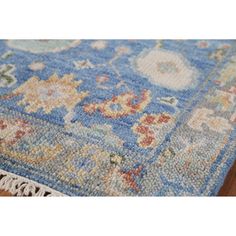 a blue rug with flowers on it and fringe trimming around the edges is laying on top of a wooden floor