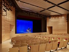 an empty auditorium filled with chairs and a projector screen on the wall behind it