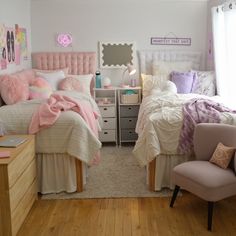 two beds in a bedroom with pink and white decor on the walls, along with a chair