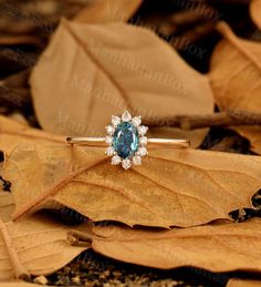 an engagement ring with a blue stone surrounded by leaves