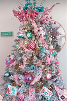 a decorated christmas tree with pink, blue and green ornaments