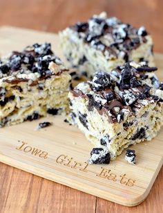 two pieces of cake sitting on top of a cutting board with chocolate chips and oreos