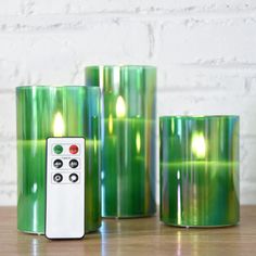 three green candles with remote controls sitting on a table