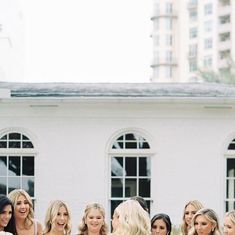 a group of women standing next to each other in front of a white building with windows