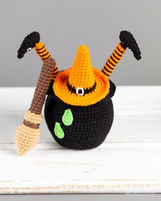 a crocheted witch's hat and broom sitting on top of a white table