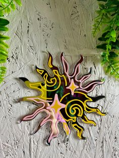 a colorful clock sitting on top of a white table next to green plants and leaves