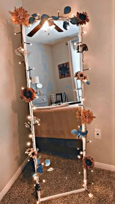 a mirror that has flowers on it and lights in front of it, reflecting the room