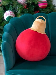 a large red ball sitting on top of a green chair next to a christmas tree