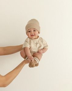 a man holding a baby in the air with his legs spread out to touch it