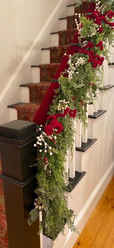 some red roses and greenery are on the banisters at the bottom of stairs