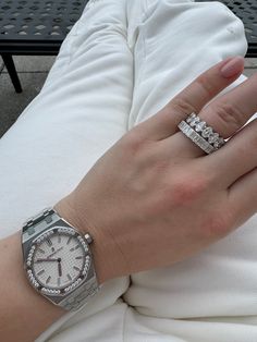 a woman's hand with two rings on her wrist and a watch on her arm