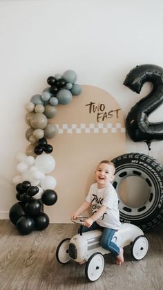 a young boy is sitting on a tricycle in front of some balloons and numbers