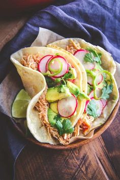 three tacos with radishes, cucumbers and cilantro on top