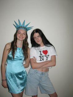 two young women dressed in costumes posing for the camera with one wearing a statue of liberty t - shirt