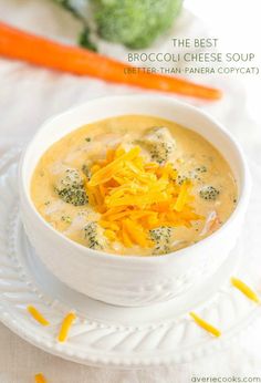 broccoli cheese soup in a white bowl on a plate next to carrots