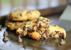 two chocolate chip cookies sitting on top of a metal pan with one broken in half