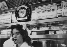 a woman standing in front of a hot dog stand