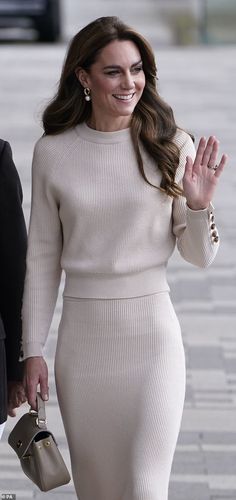 a woman in a white dress is walking down the street with her hand on her hip