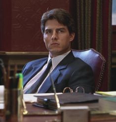 a man in a suit and tie sitting at a desk