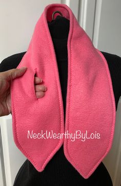 a woman wearing a pink neck warmer with her hand on the back of her shoulder