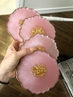 a person holding three pink plates with gold flecks on them in front of a door