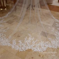 wedding veil with white flowers on the floor in front of a bride's dress