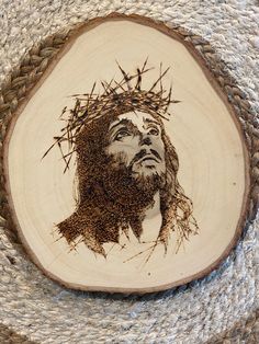 a wood slice with a drawing of jesus on it's face and crown of thorns