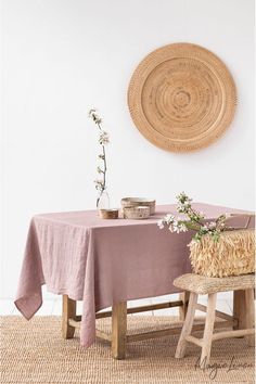 the table is set with two chairs and a round wicker wall hanging above it