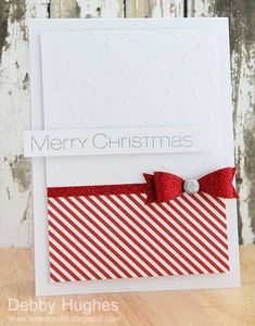 a christmas card with a red bow on the front and white back, sitting on a wooden table