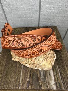 a brown leather belt sitting on top of a wooden table next to a stone slab