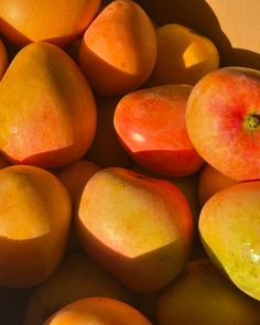 a pile of mangoes and peaches sitting next to each other