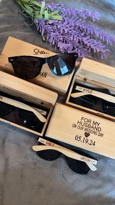 three pairs of sunglasses in wooden boxes on a bed next to lavenders and flowers