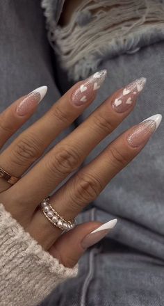 a woman's hand with some white and pink nail polishes on her nails