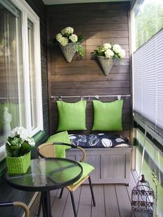 a small balcony with green cushions and white flowers