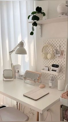 a white desk topped with a laptop computer next to a lamp and potted plant