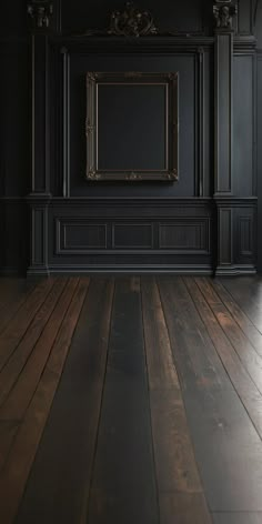 an empty room with black walls and wooden floors is pictured in this image, there is a mirror hanging on the wall