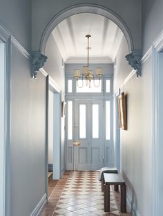 a hallway with a bench and chandelier hanging from the ceiling in front of it