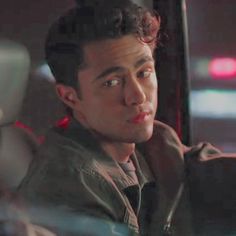 a young man sitting in the back seat of a car looking at something off to the side