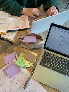 a laptop computer sitting on top of a wooden table covered in papers and sticky notes