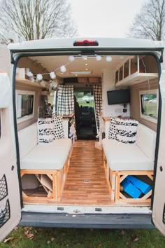 the interior of a camper van with two couches and pillows on the back