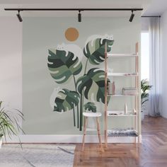 a large green leafy plant on a white wall mural in a room with wooden floors