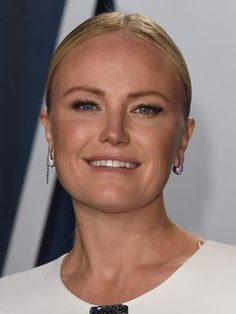 a woman with blonde hair smiling at the camera and wearing large earrings on her head