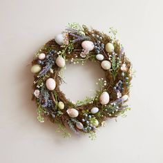 an easter wreath with eggs and greenery on a white background, hanging from the wall